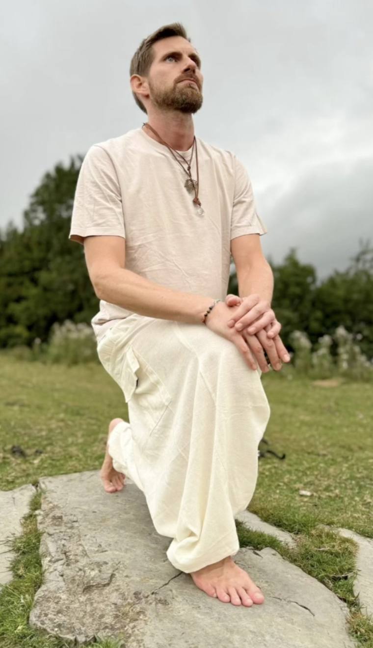 Sebas, arrodillado sobre una piedra en un prado, mira al cielo
